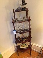 Full view of the wooden 5-tier display shelf with various glassware and decorative items arranged on it