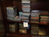 Overall view of multiple stacks of CDs on wooden shelving, showing more than 140 CDs in jewel cases and other packaging.