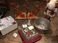 Front view of entire lot showing the Santa figure, wooden candle holders, basket, boxed glassware, and linens arranged on the floor.