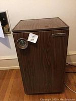 Mini refrigerator showing wood grain finish with circular temperature dial and Sanyo brand badge on front door