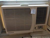 Front view of Friedrich window air conditioner installed in window with remote control on top.