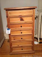 Front view of the pine side table showing 7 drawers, with some knobs missing.