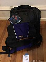 Front view of the black US Luggage computer bag and purple and black Eastpak shoulder bag, showing tags and overall condition.
