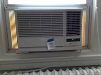 Front view of the Friedrich window air conditioner installed in the window with power cord visible and digital display showing 69°F.