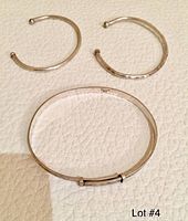 Three vintage sterling silver bracelets: one closed with detailed floral or scroll decoration and hallmark, two smaller open cuff bracelets with hammered texture.