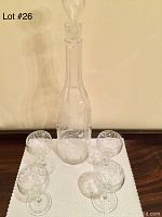 Full set showing crystal decanter with stopper and four engraved cordial glasses arranged on a surface.