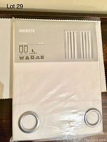 Packaged pair of IKEA MERETE white room darkening curtain panels showing front of packaging with product image and brand name.