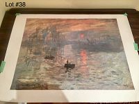 Full view of vintage Monet Sunrise print with white border taped at edges on flat surface