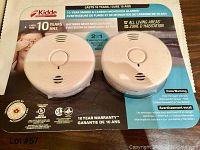 Photo of two Kidde smoke and carbon monoxide detectors on retail packaging with product and warranty details.