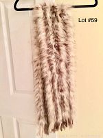 Scarf hanging vertically showing length, fluffy fur with brown spots and stripes on a creamy white base, slight fringe at ends