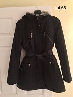 Front full view of the black ladies winter coat hanging on a hanger, showing hood, zipped and snapped front, belt, and length.