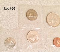 Photo showing six uncirculated Canadian coins from 1964 sealed in plastic pouches on a white leather surface.