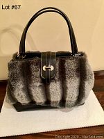 Front angled view of the handbag showing the grey faux fur texture and black leather strap with silver clasp.