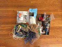 Lot laid out on wood floor showing various hand tools, cords, tape dispenser, and hardware items in plastic bags.