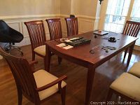Full view of dining table with two armchairs and four side chairs around it in a wood-floored room.