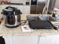 Pressure cooker and electric griddle displayed on counter, showing overall condition and size relation