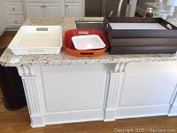 View of all trays on countertop showing white and orange plastic trays, dark brown wooden trays stacked, and metal tray.