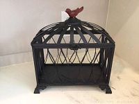 Metal black bird cage style box with red bird on top shown on white surface, close-up of cage and latch detail