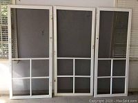 Three white vinyl framed screen doors arranged side by side showing overall structure and screen panels.