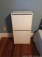 Front view of a white cabinet with two horizontal segments and no visible handles.