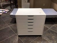 Front view of white 6-drawer chest showing drawer handles and overall condition.