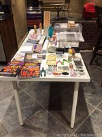 Full view of the table with all craft supplies including beads, pliers, sewing patterns, and organizer box.