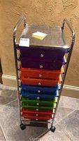 Front view of metal cart showing 10 colorful plastic drawers and metal perforated top shelf.