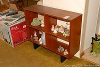 Front view of teak bookcase with four open shelves and black metal legs
