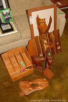 Overview of lot on couch including wall hanging with carved animal, desk organizer cabinet, two elephant sculptures, smaller carved figures.