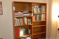 Two wooden bookshelves containing books mainly about cooking, gardening, and reference topics arranged over five shelves