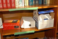 Shelf with boxed Pocketvision-22 TV, white box, and Olympus C-60 Zoom camera box