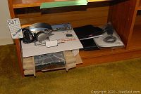 Photo of Sylvania portable DVD player with earphones and cables on packaging box, stored on shelf.