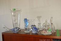 Collection of Murano glass figurines and other clear glass decorative items displayed on a wooden surface.