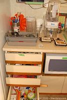 Countertop with Brita pitcher, water dispenser, cutlery, utensils in trays and kitchen drawers below