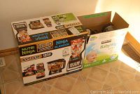 Photo of Nutri Ninja System 1500 blender and food processor combo original box next to a baby wipes box, showing product branding and features.