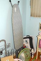 Photo showing ironing board, laundry baskets, cleaning supplies area corner with depillers