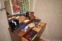 Wide angle photo showing top of dresser with wallets and scarves laid out, open drawer contains jewellery and more wallets