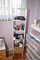 Photo of shelving unit holding vintage radios and various cameras with accessories below.