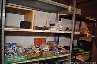 Wide angle photo showing shelves with various tools, boxes, hand tools, and electrical accessories including Black and Decker multi-tool kit bag