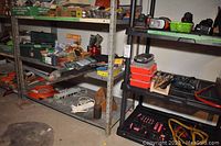 Wide shot of shelving containing various hand and power tools, orange extension cords, power bars, and toolboxes on four bottom shelves.