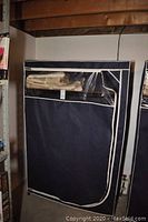 Portable wardrobe with fabric cover zipped closed and clear plastic window panel near the top, contents visible through window.