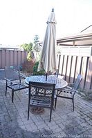 Full view of round table with four chairs and umbrella on patio