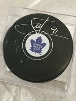 Front view of the black Toronto Maple Leafs puck showing the signature in silver ink with the number 91.