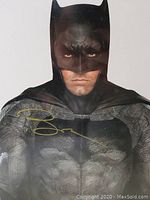 Close-up of the photo showing the gold signature on Ben Affleck's Batman costume.
