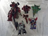 Overview photo showing all five mixed transformer toys with some detached parts on white cloth background