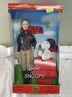 Front view of factory sealed Barbie and Snoopy collectible box showing Barbie pilot doll and Snoopy plush on doghouse with original packaging intact.