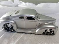 Side angle showing sleek aerodynamic vintage muscle car model body in metallic silver.