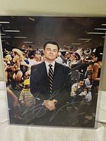 Signed 8x10 color photo of Leonardo DiCaprio from The Wolf of Wall Street showing details of the autograph and background scene.