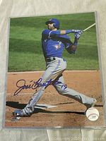 8x10 color photo of Jose Bautista swinging a bat in Blue Jays uniform, showing autograph and authentication sticker.