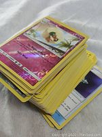 Pile of Pokemon trading cards with yellow borders. Foil shiny card of Slakoth visible on top.